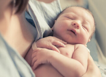 Ein neugeborenes Baby liegt in den Armen der Mutter. 